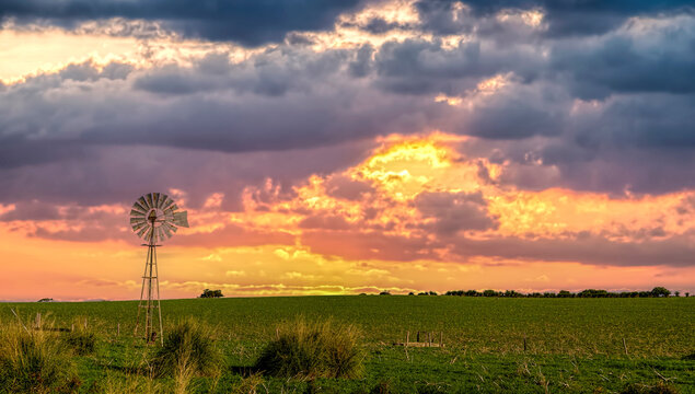 Sunset over a traditional metal windmill in rural outback landscape, Western Australia, Australia