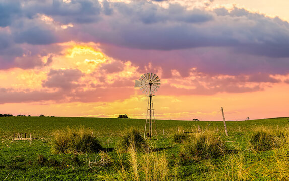 Sunset over a traditional metal windmill in rural outback landscape, Western Australia, Australia