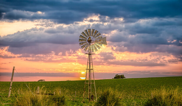 Sunset over a traditional metal windmill in rural outback landscape, Western Australia, Australia