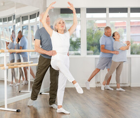Gracious old woman doing choreography in pair with man during ballet classes in dance studio