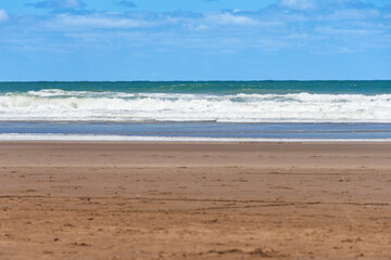 Waves, foam, sky and sand that make up the shore of the sea beach.