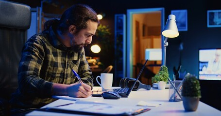 Self employed broker investor in home office checking stock exchange profit, calculating using pen...