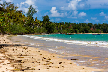 Tropical sandy beach with traditional boats moored in a warm ocean