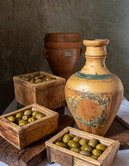 vintage clay vases with small wooden boxes filled with plump green olives, evoking a timeless charm and Mediterranean allure.