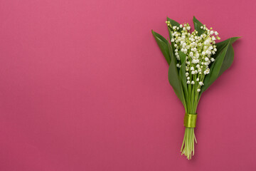 Lilies of the valley flowers on color background, top view.