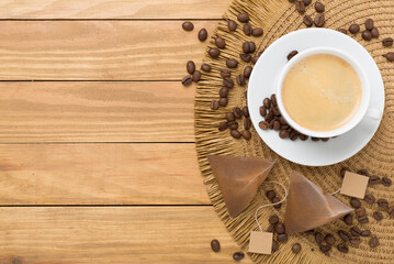 Cup of coffee made using pyramid on wooden background, top view