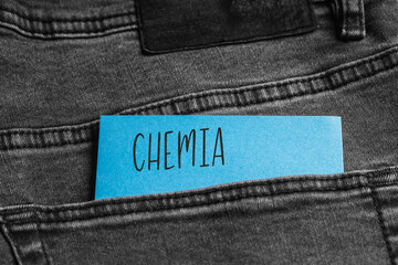 Blue card with a handwritten inscription "Chemia", inserted into the pocket of gray pants jeasnow (selective focus), translation: Chemistry