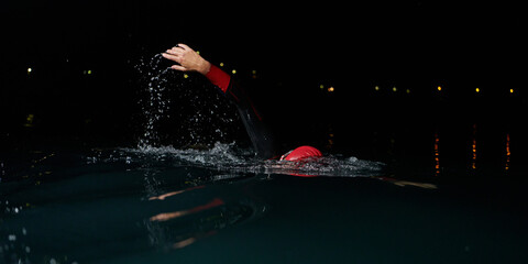 A determined professional triathlete undergoes rigorous night time training in cold waters,...