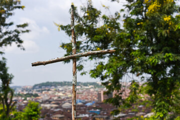 Ibadan, Oyo, Nigeria - April 15, 2024: A wooden cross against the Ariel view of Ibadan city.