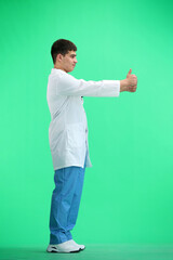 The doctor, in full height, on a green background, shows his thumbs up