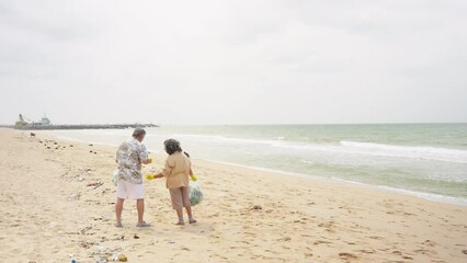 Asian family senior couple travel ocean on summer holiday vacation. Elderly man and woman picking up plastic trash and garbage together on the beach. Environmental conservation waste pollution concept - Powered by Adobe