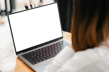 A woman is sitting at a desk with a laptop open. The laptop screen is blank, and the woman is looking at it. Concept of focus and concentration
