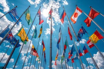 International flags of various countries wave against a bright blue sky with fluffy clouds