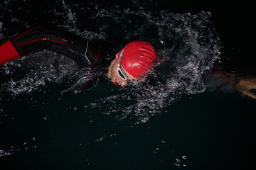 A determined professional triathlete undergoes rigorous night time training in cold waters,...