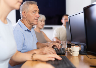 Computer lessons for elderly people in a nursing home. Group of seniors learning to use computers...