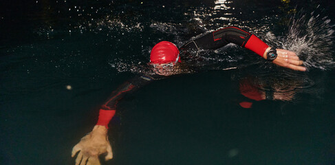 A determined professional triathlete undergoes rigorous night time training in cold waters,...