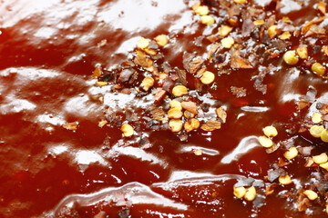 Macro shot of chili flakes on chili sauce