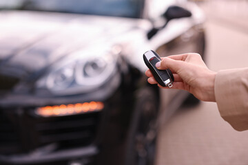 Woman holding car flip key near her vehicle outdoors, closeup