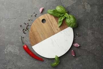 Cutting board, basil, pepper, chili peppers and garlic on grey table, flat lay. Space for text