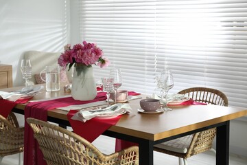 Pink peonies on table with beautiful setting and rattan chairs in dining room