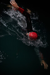 A determined professional triathlete undergoes rigorous night time training in cold waters,...