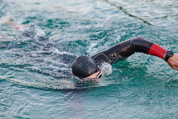 A professional triathlete trains with unwavering dedication for an upcoming competition at a lake,...