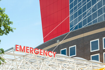 An emergency sign outside a hospital. The illuminated red letters spell emergency and are affixed...