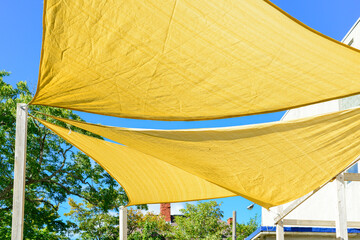 Multiple large summer nylon patio sun shade umbrellas, sunny yellow color with wooden supports. The...