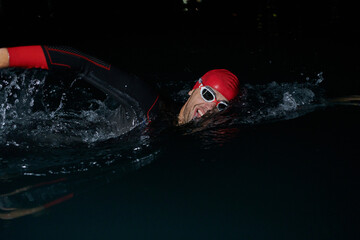 A determined professional triathlete undergoes rigorous night time training in cold waters,...