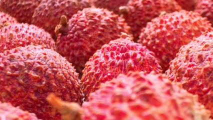 A vibrant close-up showcases lychee fruits, their spiky red shells bursting with texture and color....