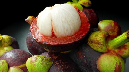 Behold the allure of the mangosteen, its deep purple rind embraces the creamy white flesh within, a...
