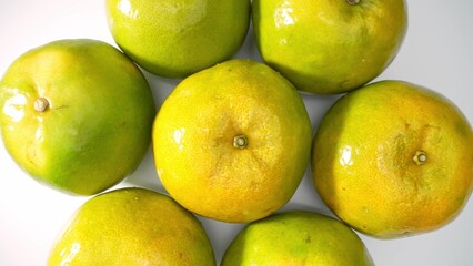 A cluster of vibrant green oranges, snugly nestled, their glossy skins gleaming under the light....