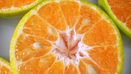 Vivid imagery bursts forth from sliced green-skinned oranges, their juicy segments gleaming against...
