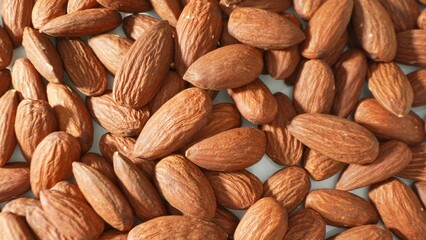 Fototapeta premium In a tight frame, whole almonds exhibit their distinctive brown shells, each crease a testament to their natural resilience. Packed closely, they flaunt their earthy allure and textured surface. 