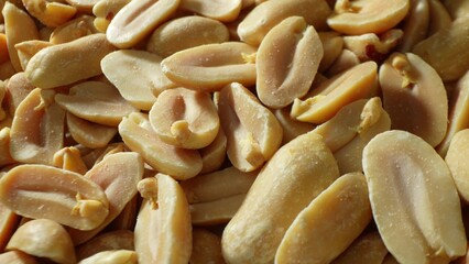 Roasted peanuts, with their split halves and lightly salted surfaces, boast a spectrum of hues from pale tan to rich brown, accentuating their crunchy texture and rich flavor.
