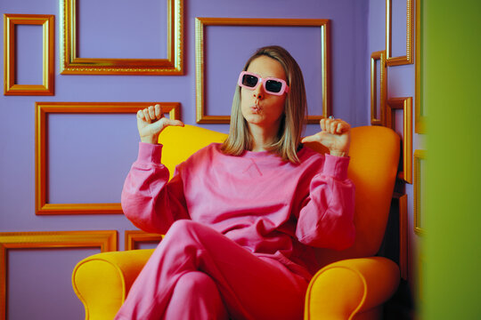 Arrogant Woman Sitting on Armchair Pointing to herself. Cool girl feeling self-obsessed and megalomaniac 
