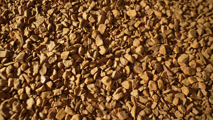 Close-up, freeze-dried coffee granules reveal a rugged, uneven texture, in hues of deep brown. Each...