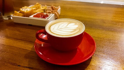view of latte coffee in red cup isolated on wooden table background.