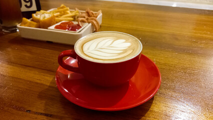 view of latte coffee in red cup isolated on wooden table background.