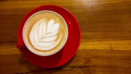 view of latte coffee in red cup isolated on wooden table background.