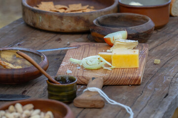 Onions and cheese on a wooden cutting board, ceramic bowls on a wooden table, decorations for a medieval fair
