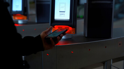 Close-up of passing through electronic turnstile with barcode scanner. Media. Using smartphone to...