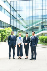 オフィスビルの前に並ぶ多国籍ビジネスパーソンのグループ