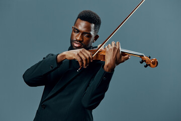 Elegant African American Violinist in Black Suit Performing on Gray Background in Classic Music...