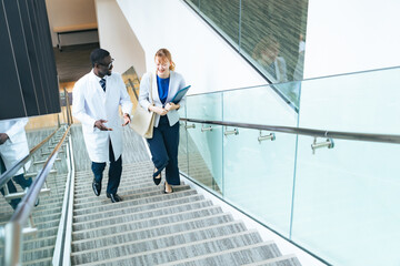 A researcher in a white coat and a female business person having a conversation in an office