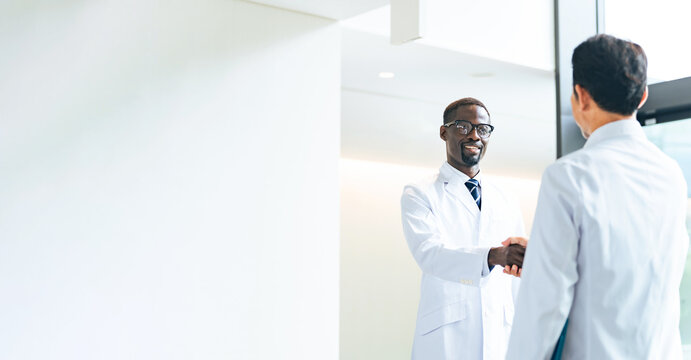 Multinational group in white coats shaking hands in a lobby