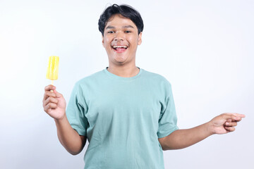 Cheerful Young Asian Man Holding Ice Cream While Pointing To Side For Advertisement Isolated On White Background