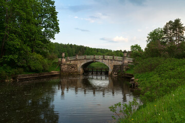 View of the Slavyanka River and the Viscontiev Bridge in the Pavlovsk Palace and Park Complex on a sunny summer day, Pavlovsk, Saint Petersburg, Russia