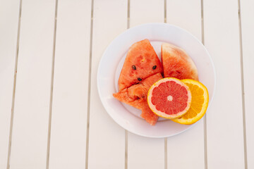 Sliced Watermelon and Citrus Fruits on a White Plate During a Sunny Day