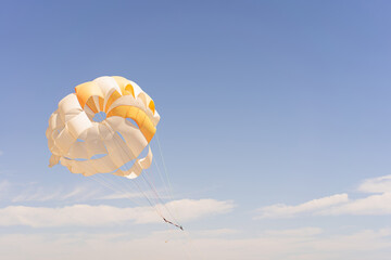 The parachute is fully inflated, showcasing vivid yellow and white colors as it glides through the...